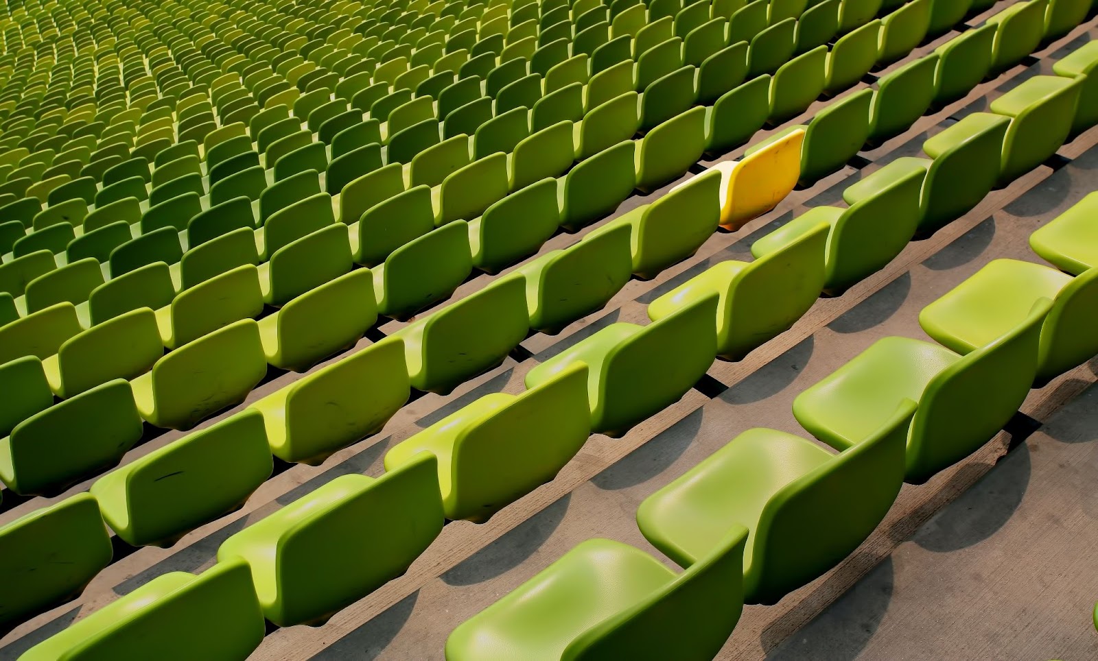 Asientos de estadio que son todos verdes excepto uno amarillo.