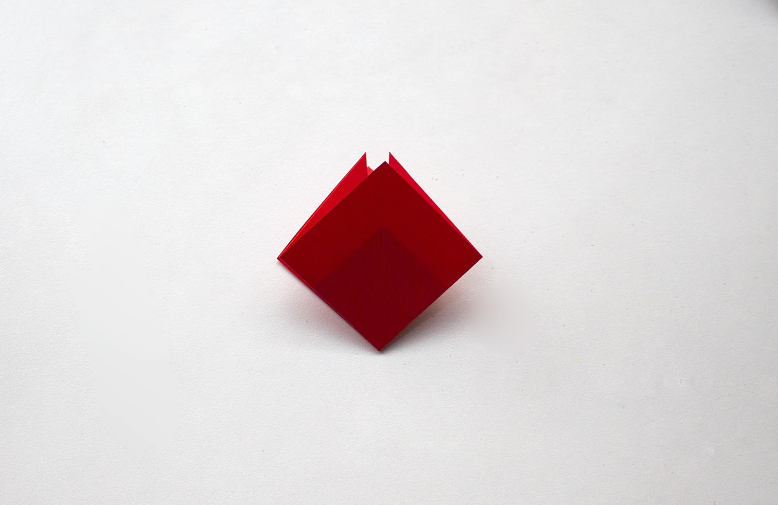 Origami poppy flower step 8: red diamond with open folds pointing upward