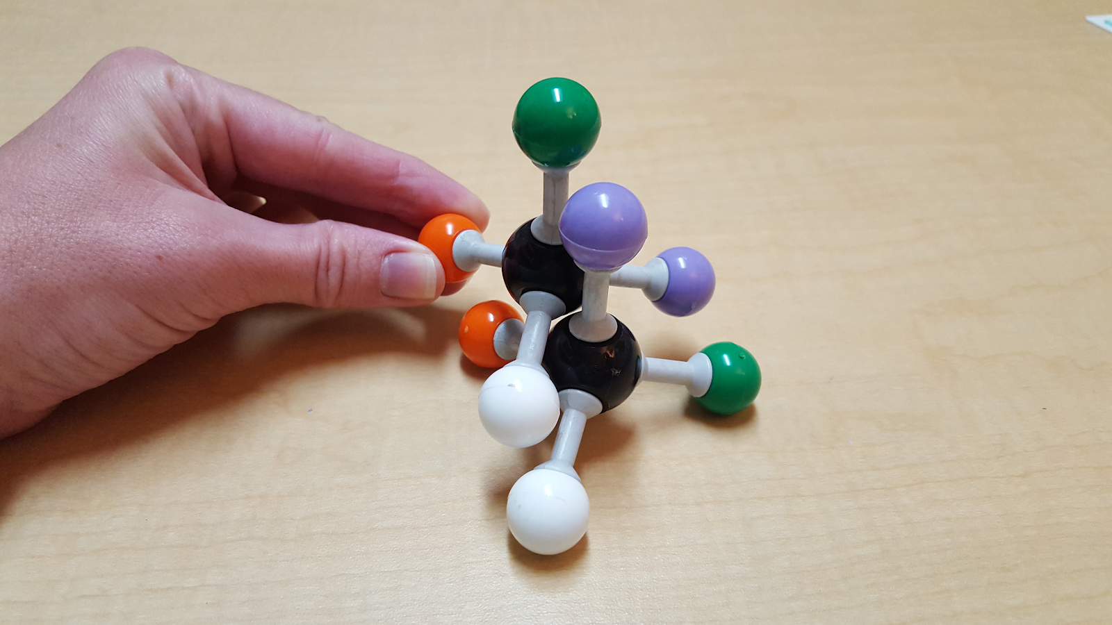 Two models of CHBrClF which are being held on top of one another with three sets of the atoms aligned. The other two sets of atoms do not match up. 