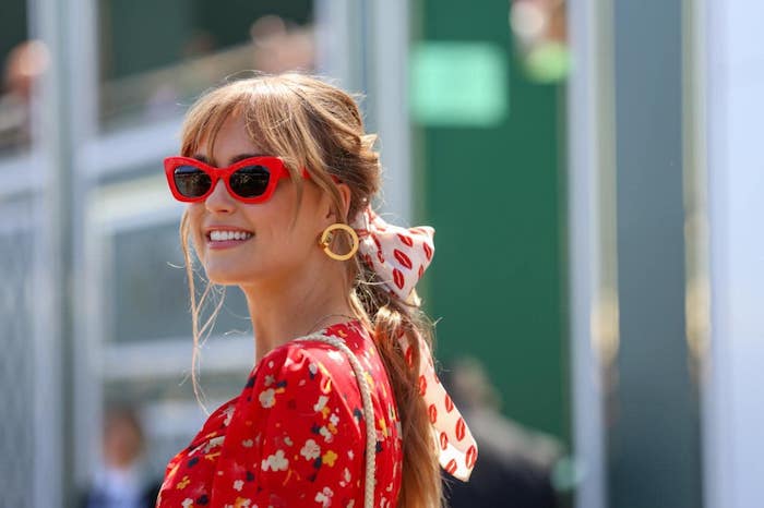 Weißes Haarband mit Küssen, Sonnenbrille mit roten Rahmen, rote Bluse mit Blumenmuster 