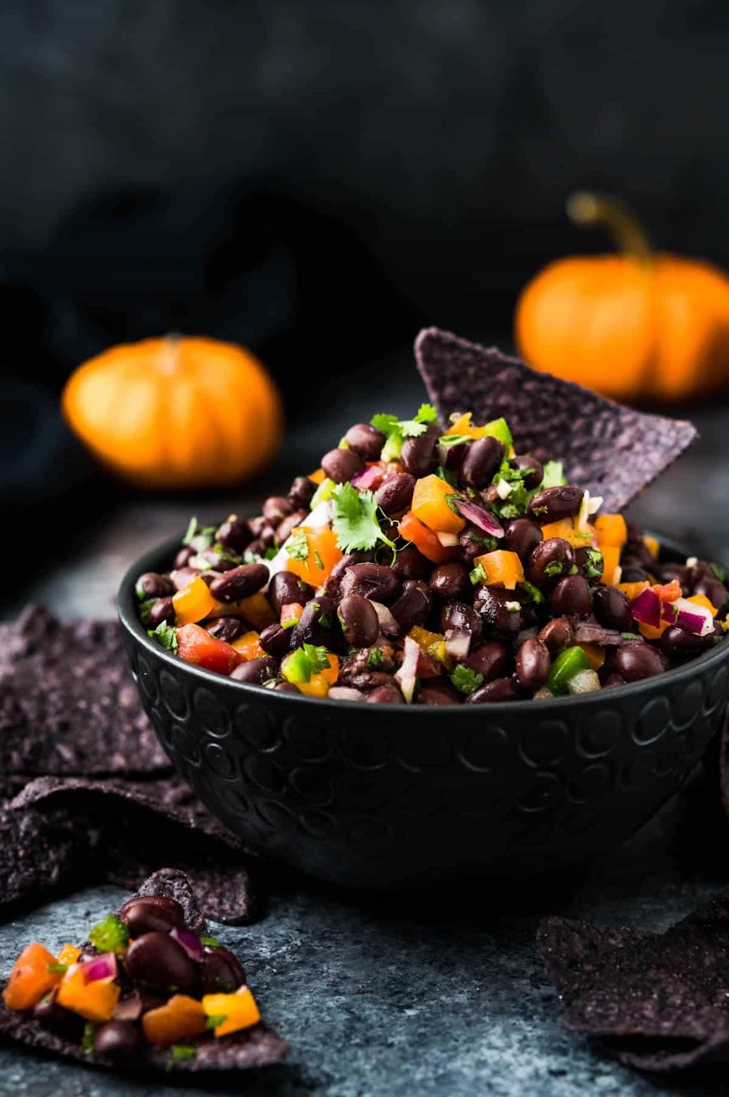 Healthy bean dip served in a black bowl with pumpkins in the background.