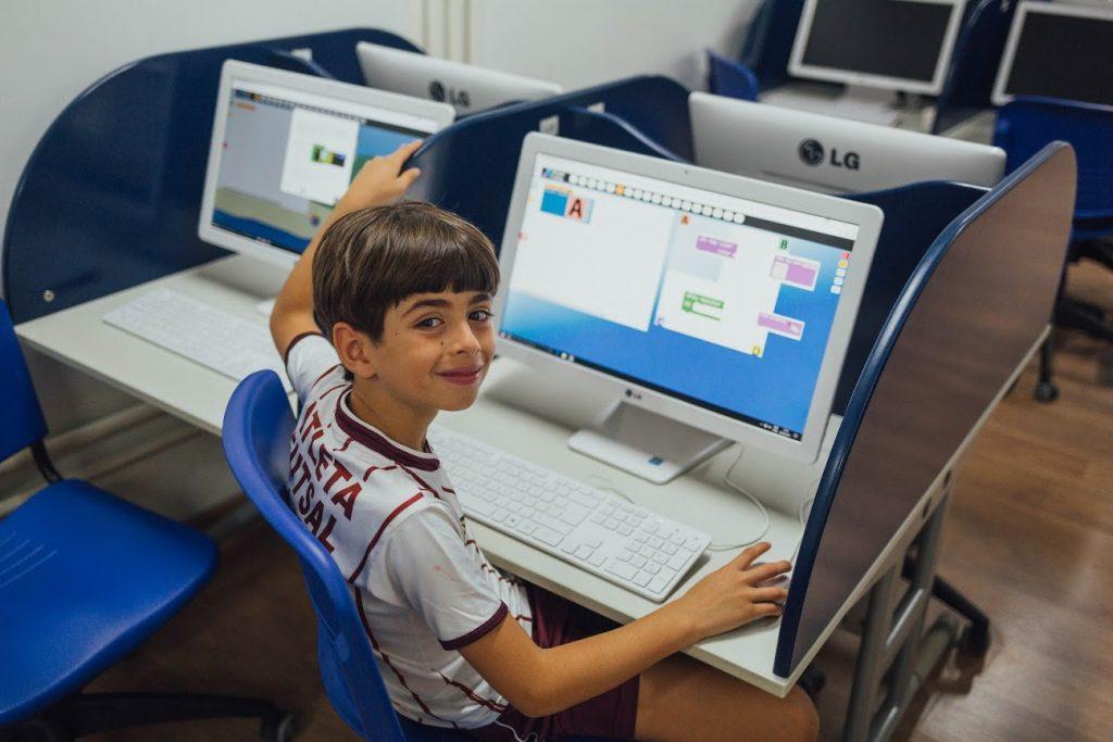 Menino sentado em frente a computador

Descrição gerada automaticamente com confiança média