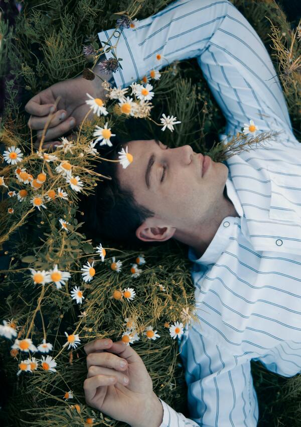 homem deitado na grama com flores em volta