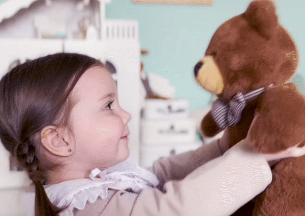 A sweet little girl kissing and hugging her Smart Teddy.