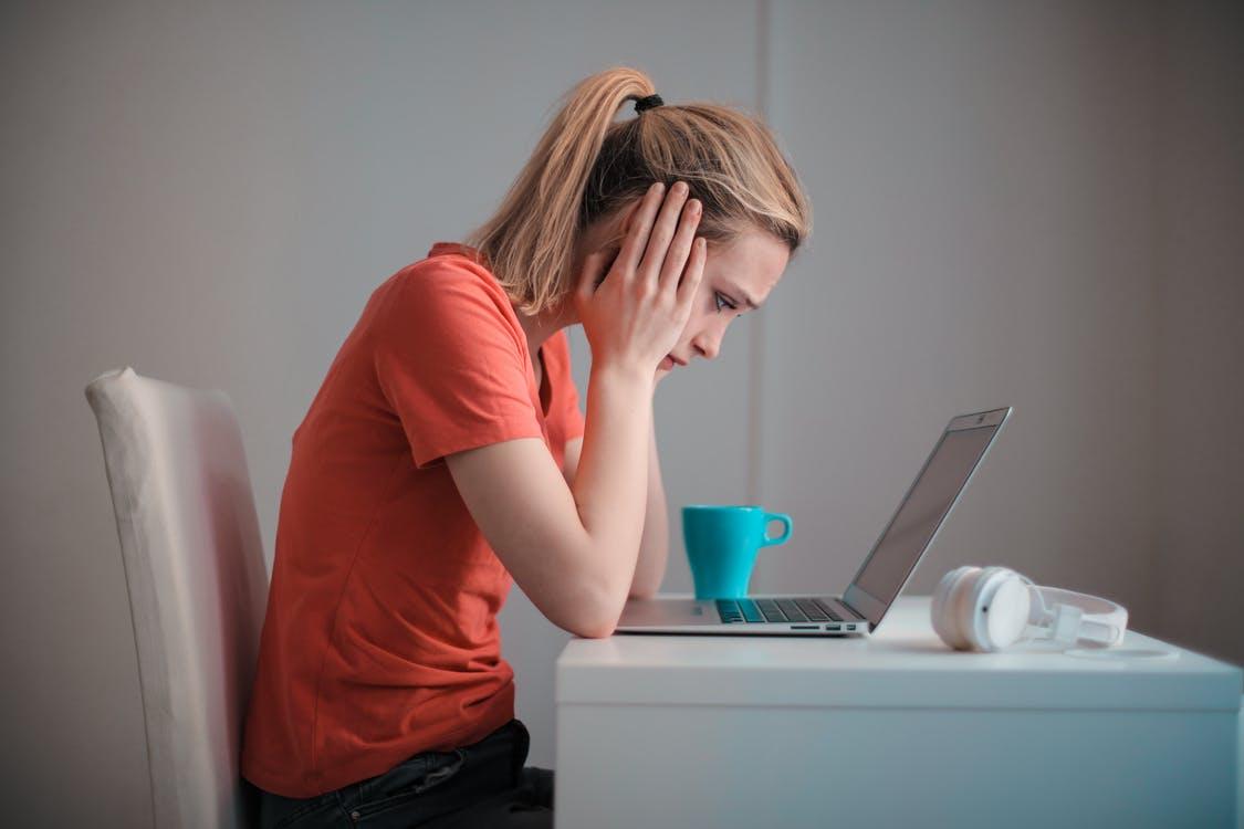 A troubled woman looking at her laptop screen