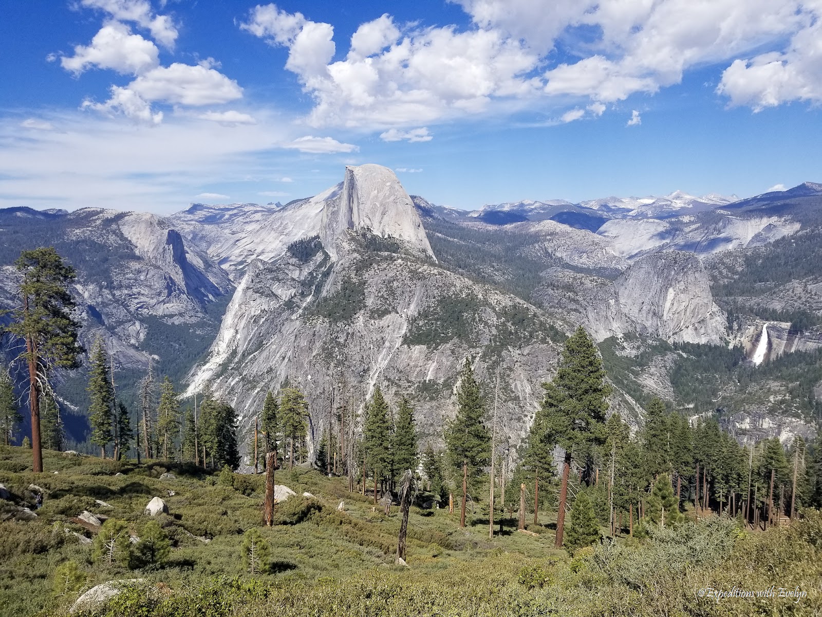 Half Dome towers above glacier-carved granite valleys with Nevada Falls in the background.  Pine trees dot the foreground.