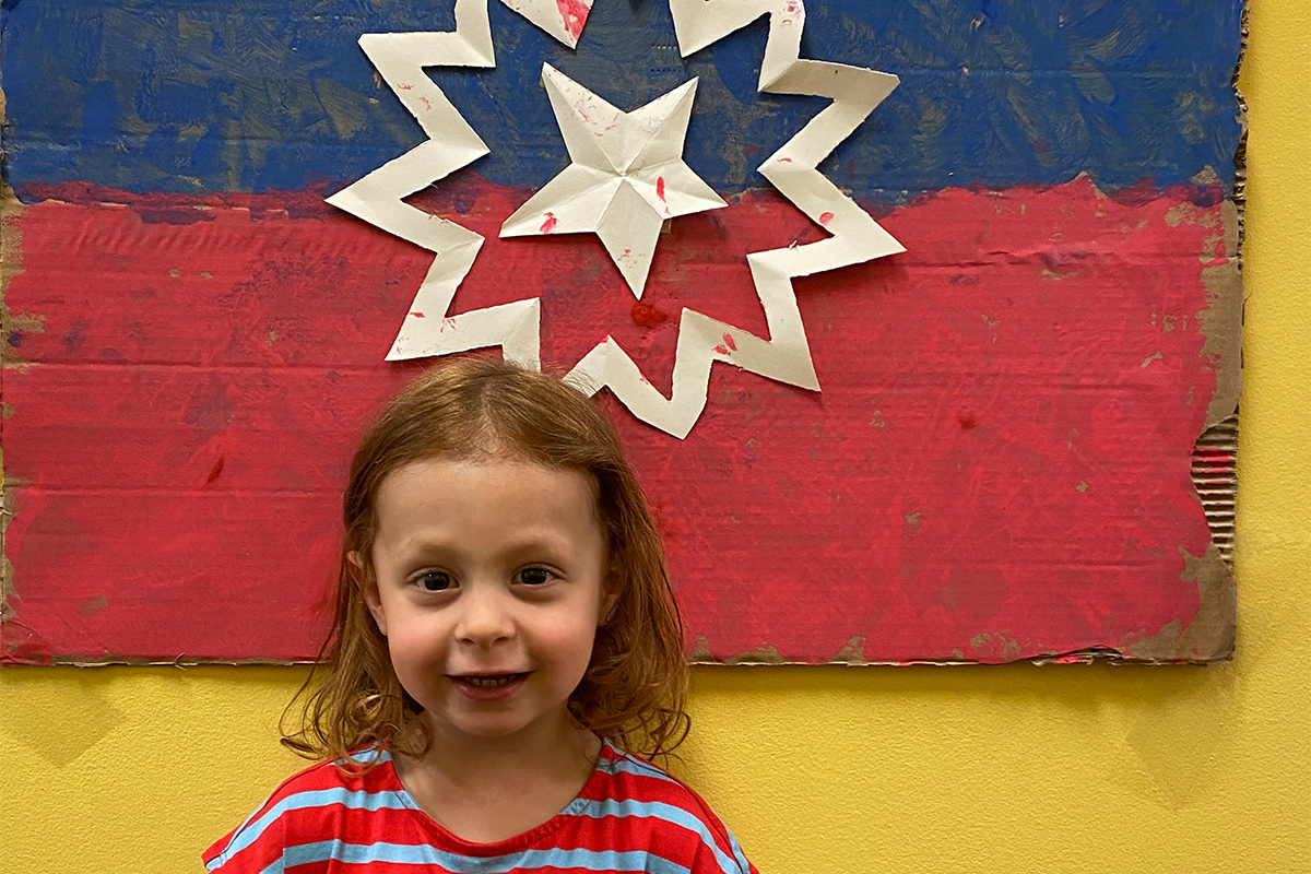 child standing in front of juneteenth flag made at casa