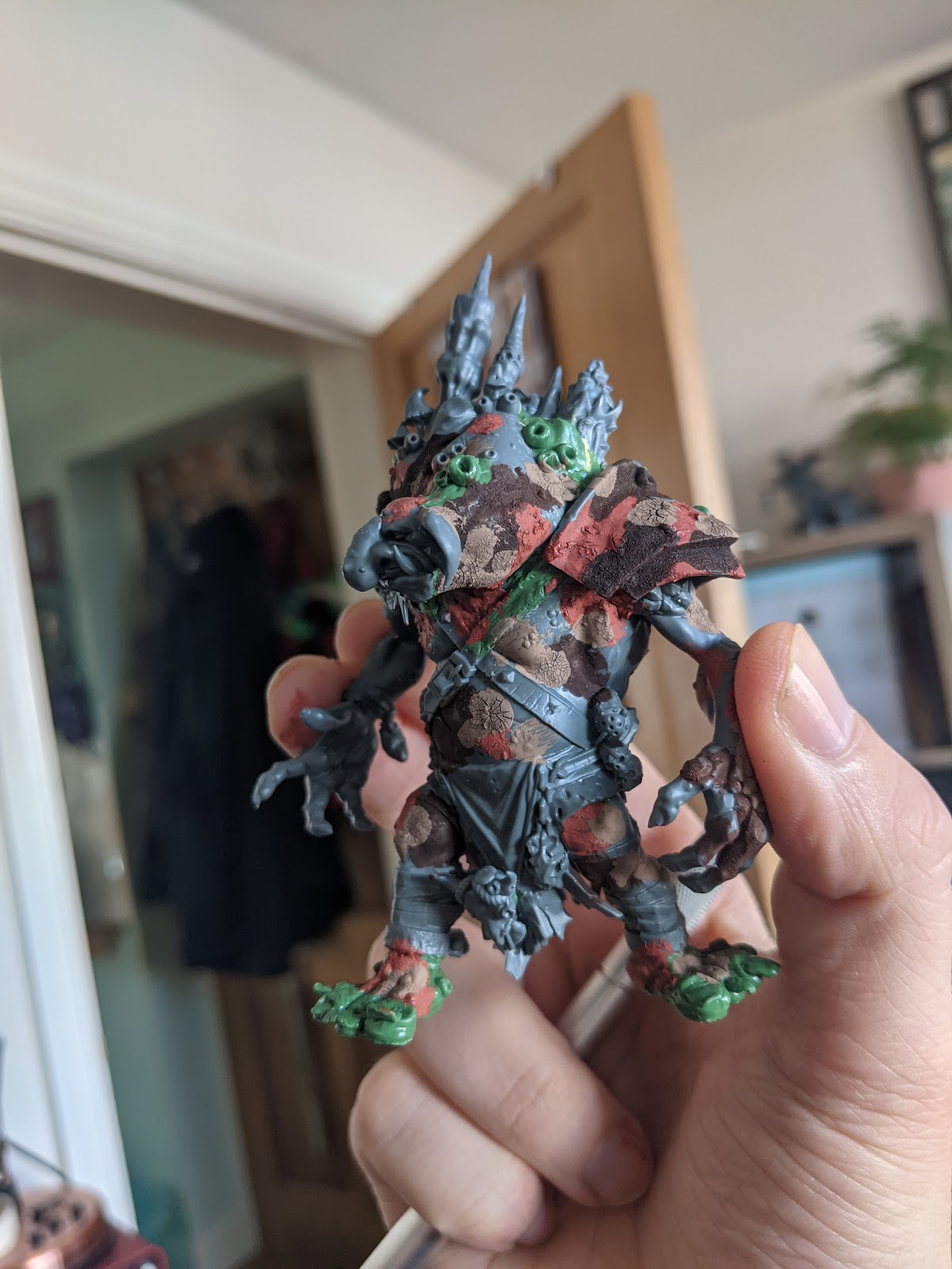 A model troll in grey plastic and green modelling putty, made from parts of several models and partially painted with textured paint.