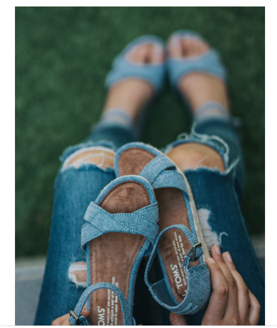 A lady holding her blue sandals