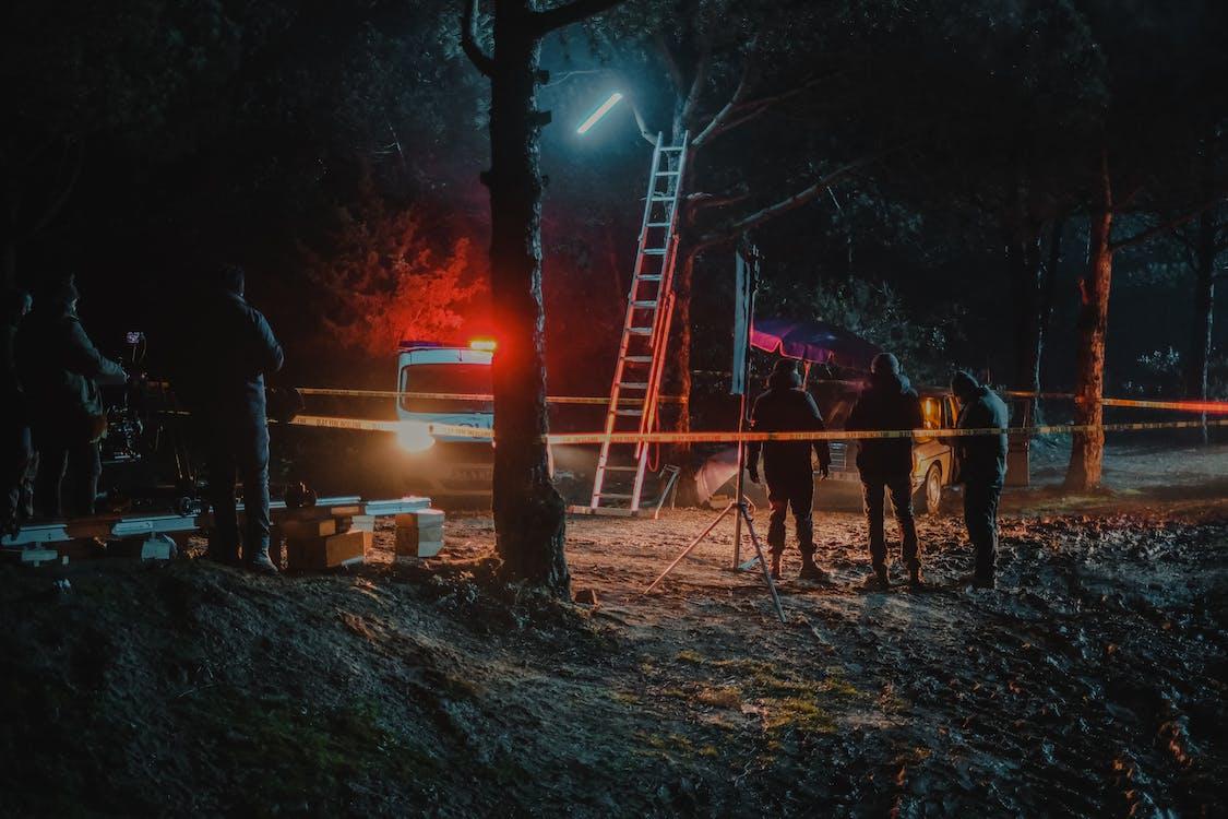 White Oak Security shares a photo of a Group of colleagues investigating crime scene fenced with tape among trees at dark night Stock Photo