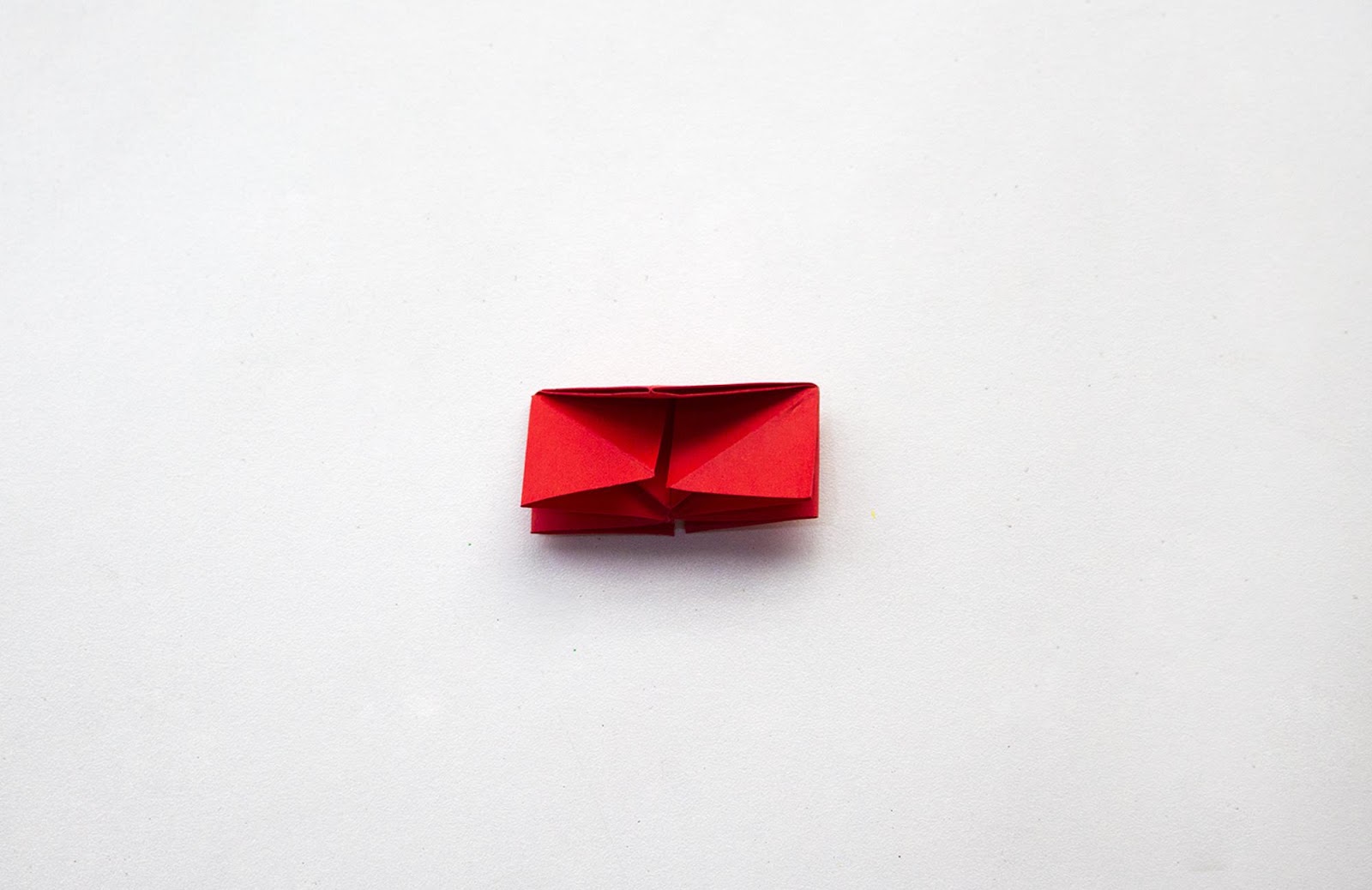 Red paper house with top folded toward center for origami flower
