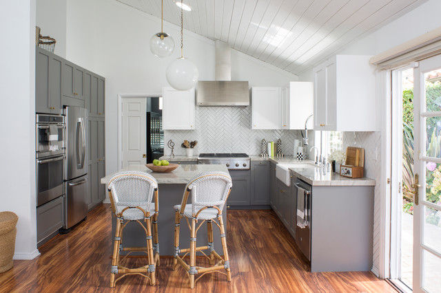 a beachy bright kitchen remodel from hgtv. white shaker upper cabinets are contrasted by grey shaker base cabinets. a warm wood floor keeps the space feeling like a traditional beach cottage