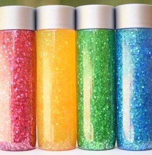 Plastic sensory bottles with blue, green, yellow and red glitter inside.