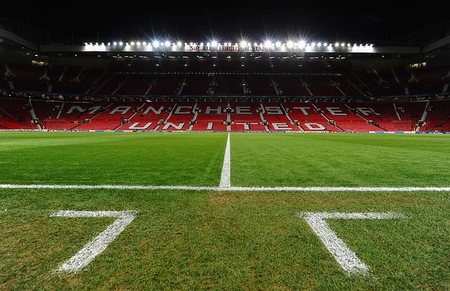 An empty Old Trafford football stadium with the words “Manchester United” written on red seats 