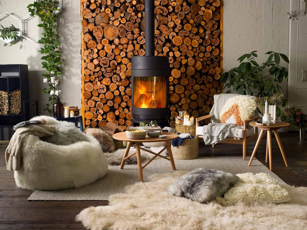 Warm living space with lots of fluffy seating, rug and pillows surrounding a fireplace
