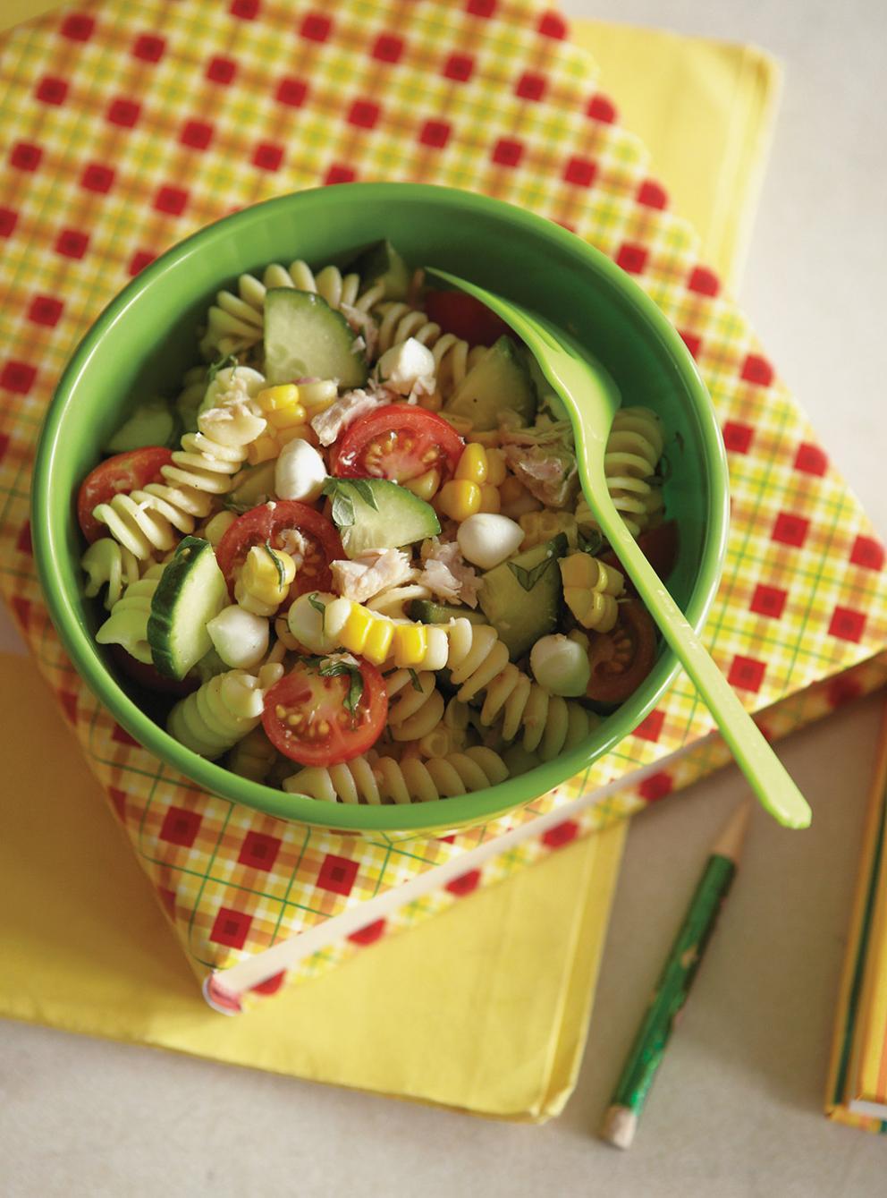 A bowl of pasta salad with a spoon

Description automatically generated