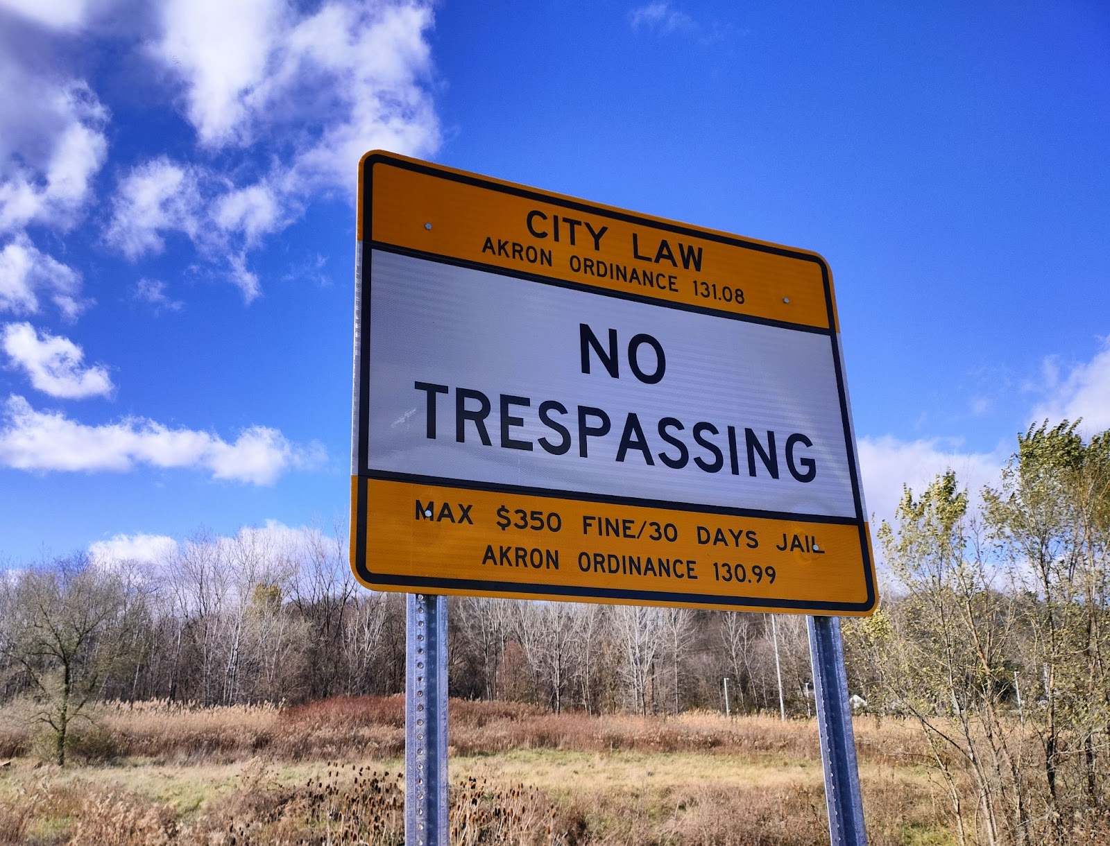 A sign posted outside of White Pond wetlands that reads, City Law, Akron Ordinance 131.08, NO TRESPASSING, Max $350 fine/30 Days Jail, Akron Ordinance 130.99