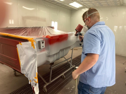 AJ Dorman paints pickup truck bed in a spray booth in Auto Body repair class using a spray gun.
