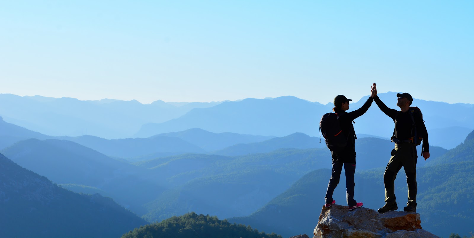 Two people high fiving on a mountain top 