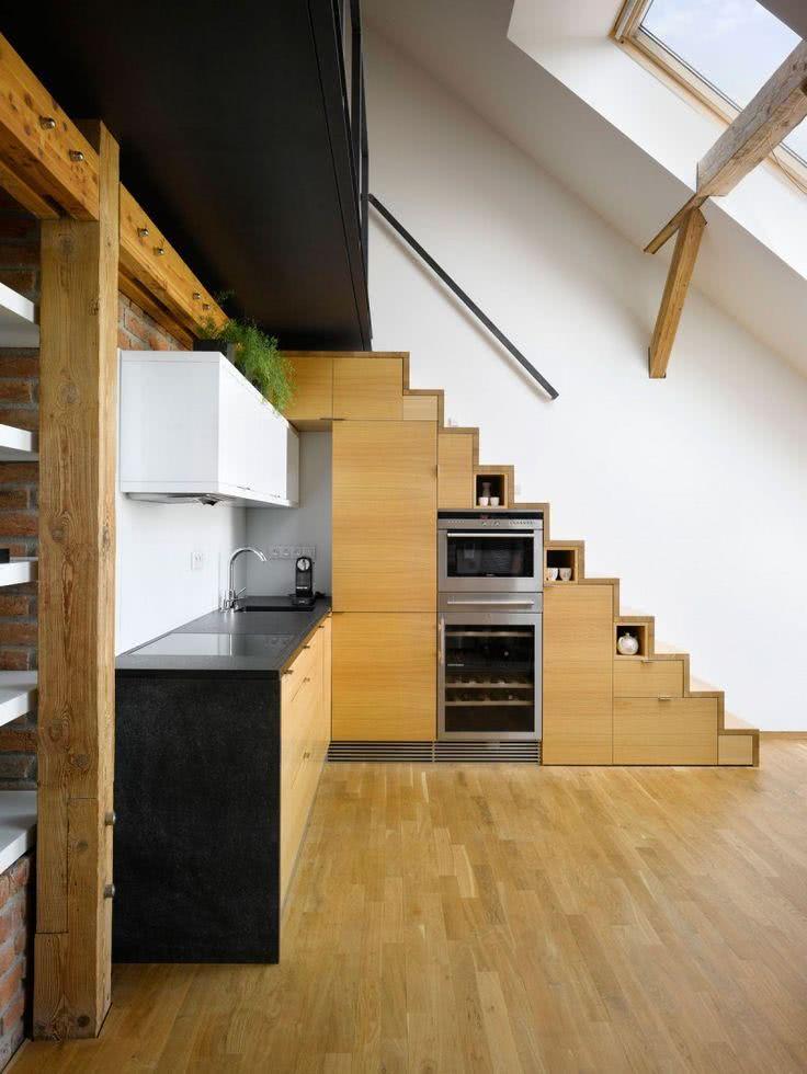 Nesse projeto a escada serviu também como um armário para cozinha. Feita de madeira, ela foi inserida com muita precisão no ambiente. 