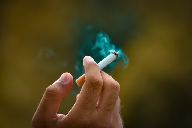 Gelegenheitsrauchen - eine Zigarette in der Hand mit grünem Rauch