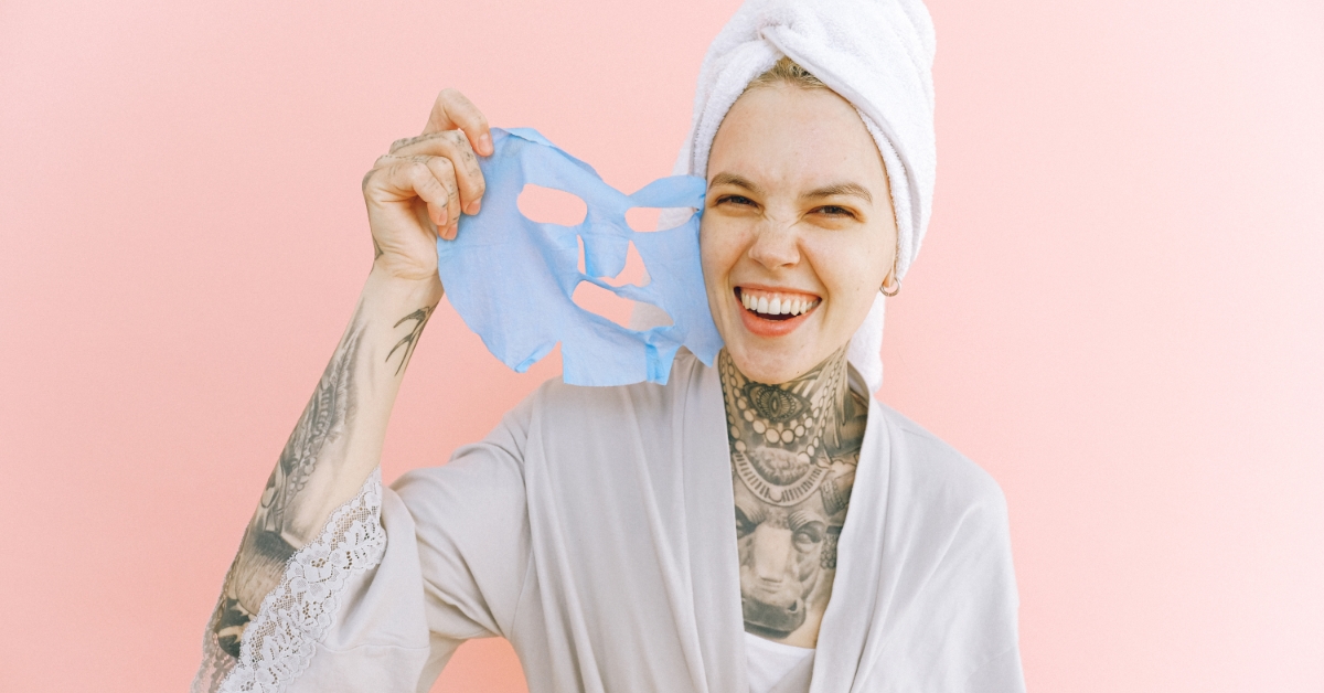 Happy lady with face mask wearing loose clothing with tattoo on body
