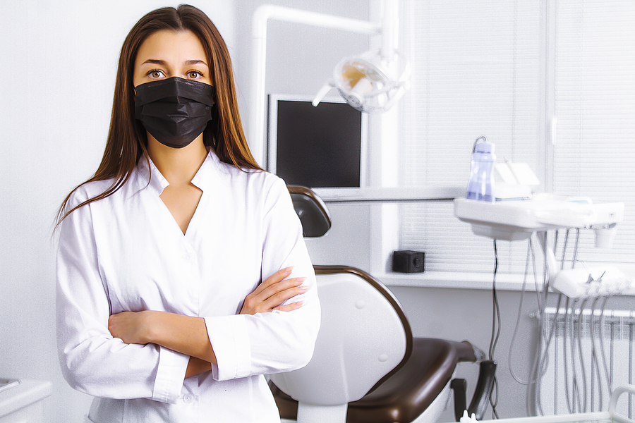 Dentist in her practice and wearing a face mask.