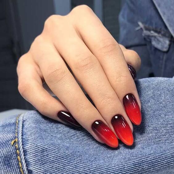 Imagem com unhas de acrigel com degradê de preto, vermelho e laranja
