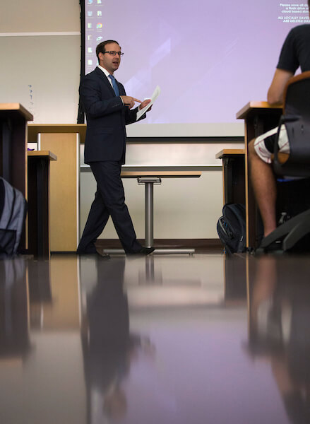 a college professor lectures in front of a projector screen on the first day of classes 