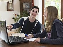 Zwei Jugendliche sitzen vor einem Laptop.