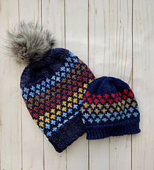 two knit hats in black with colorwork on wooden background