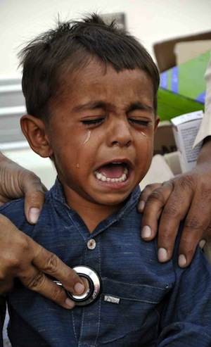 A child cries with pain while he undergoes a medical check-up at a makeshift hospital. Experts say healthcare facilities in Tharparkar leave a lot to be desired. Credit: Irfan Ahmed/IPS