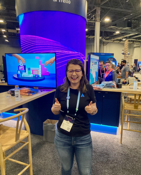 Erika Storli, Trello Marketing employee, giving a thumbs up by a booth