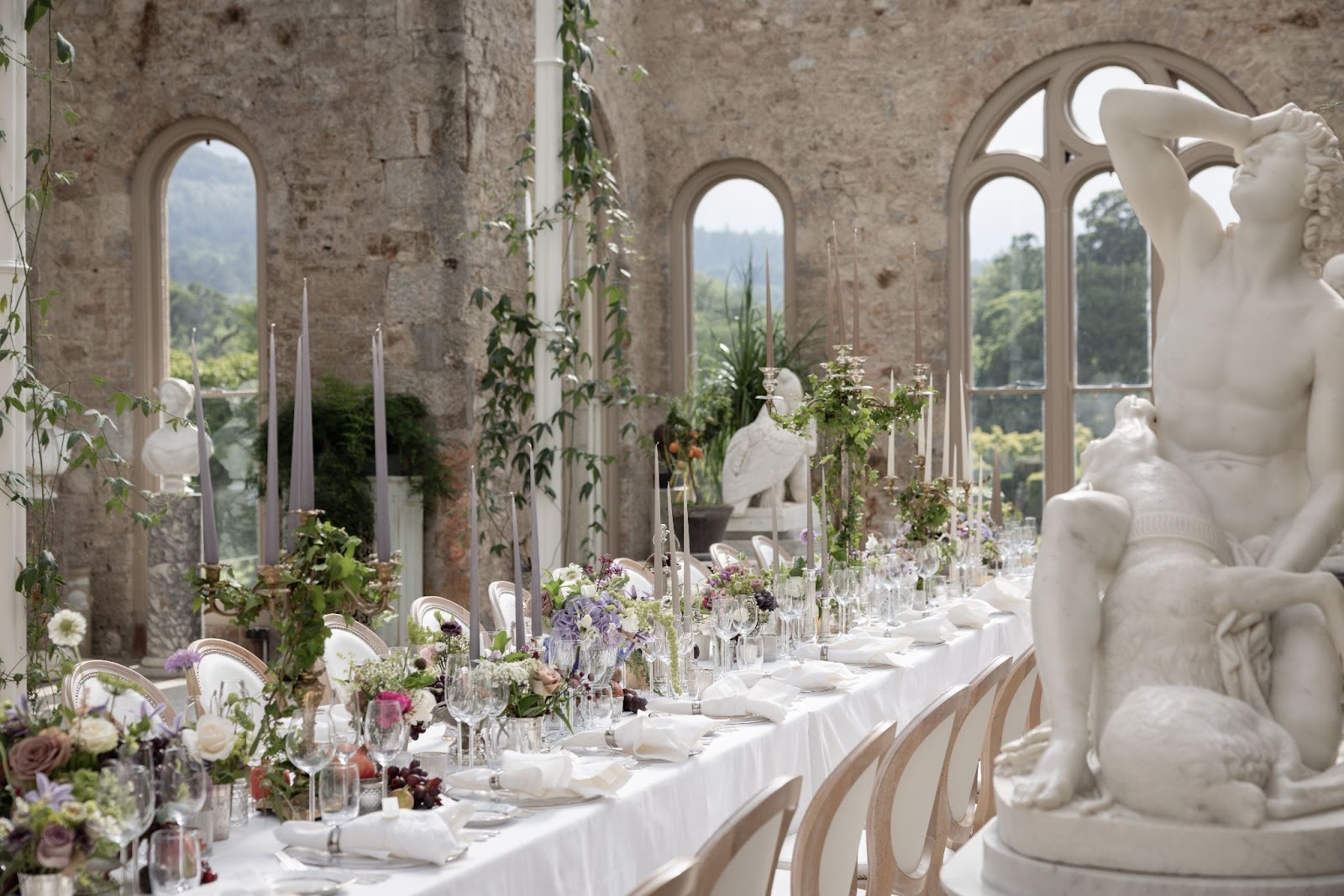 Seasonal botanicals and stunning statues fill the wedding reception by Tara Fay.