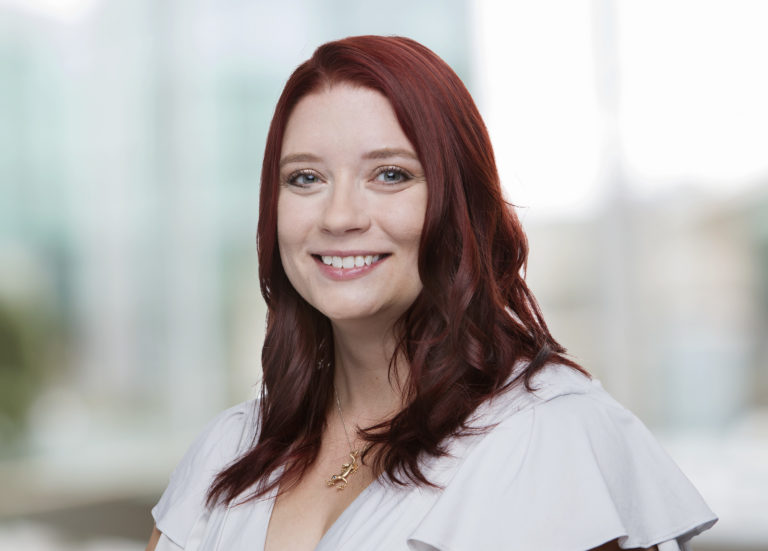 Headshot of a smiling woman with fair skin and burgundy hair.