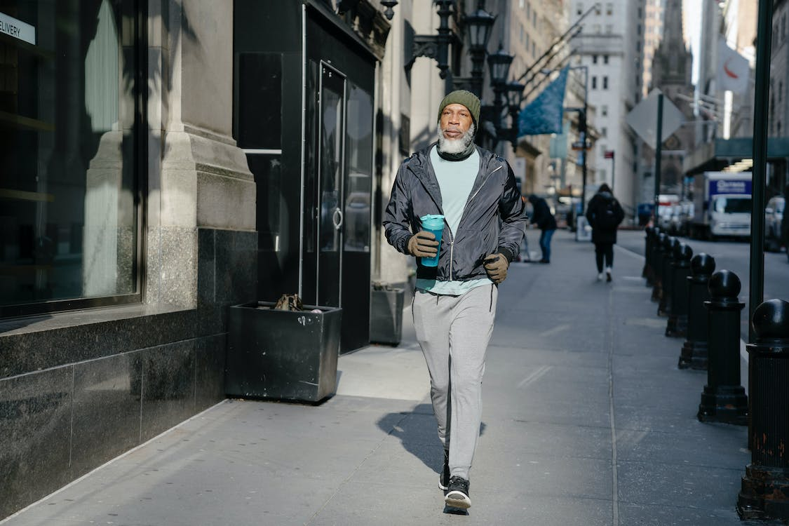 a senior black man walking on pavement in city
