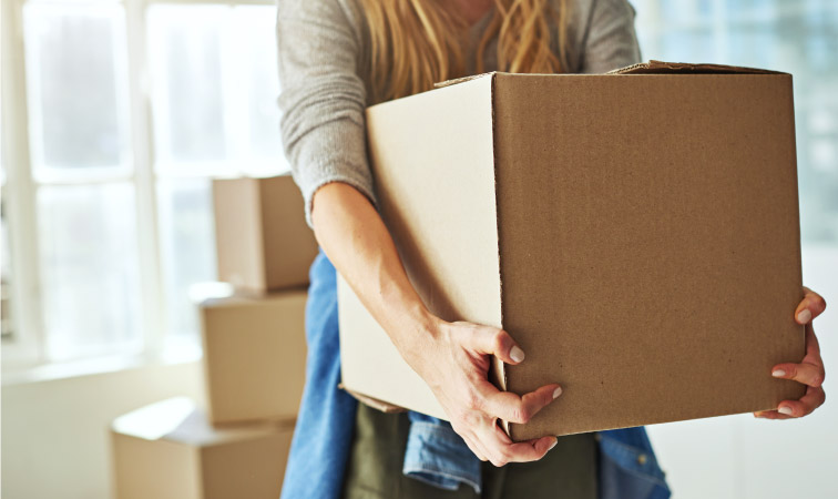 A woman carrying a cardboard moving box