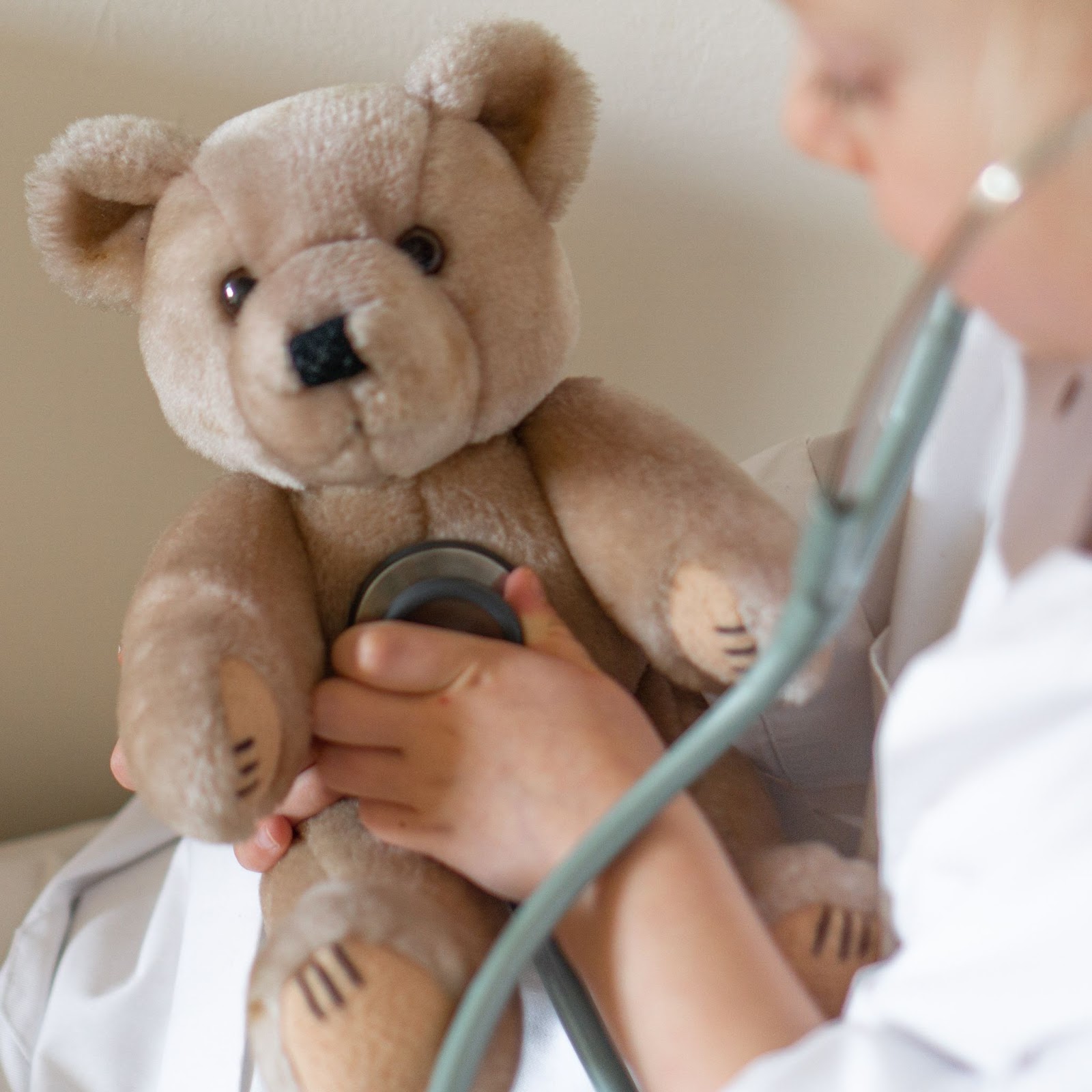 kid giving teddy bear a checkup, imagination, play doctor, role playing
