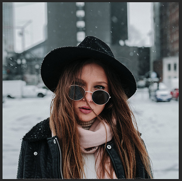 Stock image of woman in hat and sunglasses against blurred snowy city background. Woman's figure is exactly outlined in marching ants to denote selection by selection tool after refinement