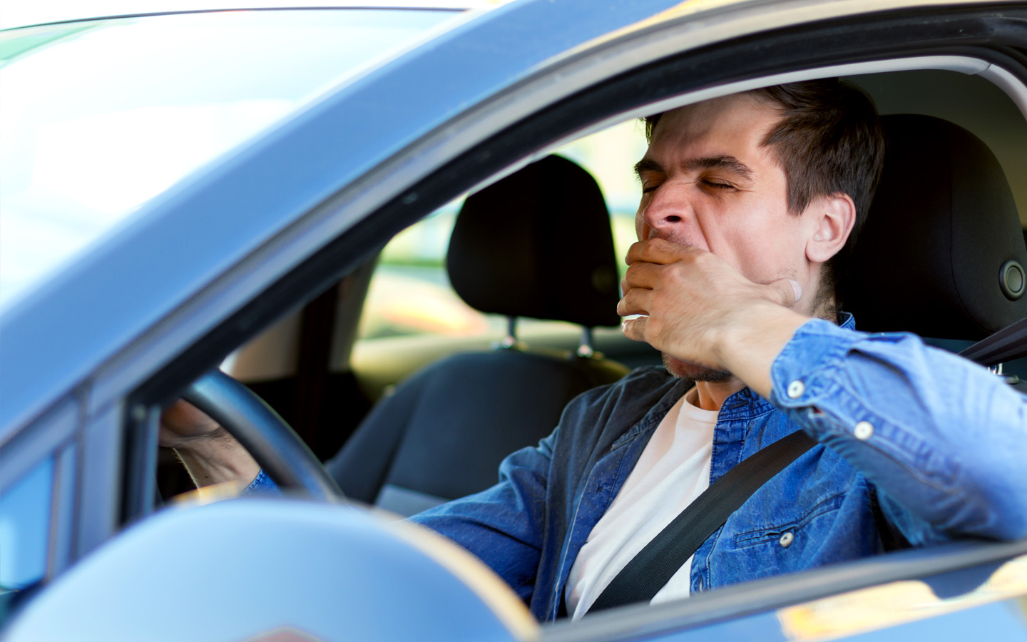 man yawning in car