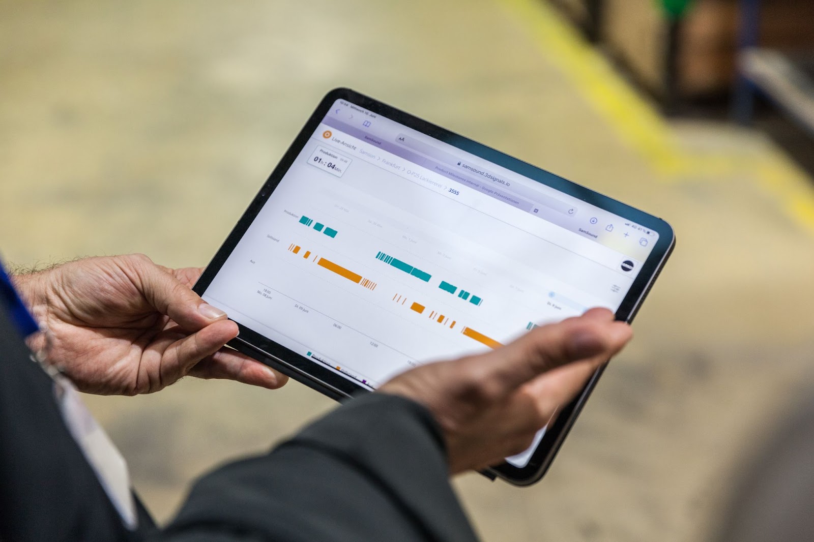 A photo of a man's hand with tablet showing graphs