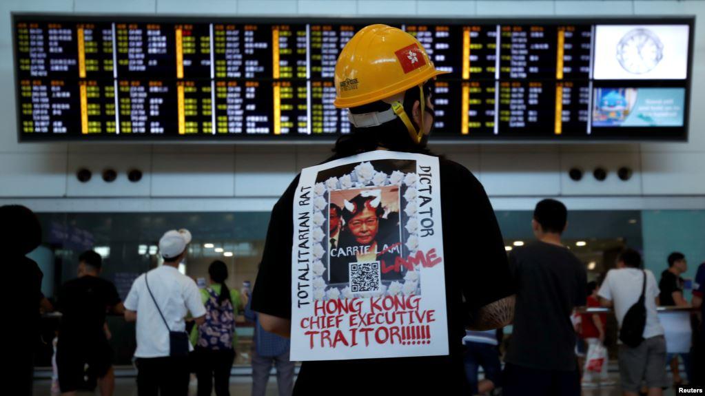 一名示威者在香港机场背负一张称香港特首林郑月娥为独裁者的抗议标语。(2019年7月26日)