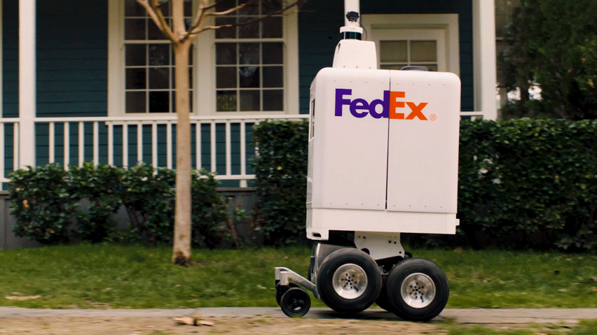 A Fedex robot traveling on a sidewalk.