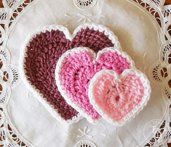 three different sizes of crochet hearts on doily