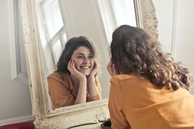 A beautiful young lady smiling at a mirror