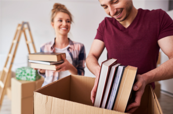 A young couple is packing books in moving boxes for their move.