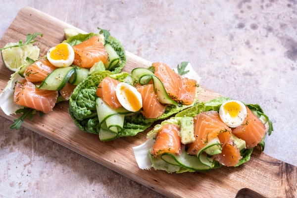 Salmon tacos with zucchini and soft-boiled egg, lettuce-wrapped, and served on a wooden board