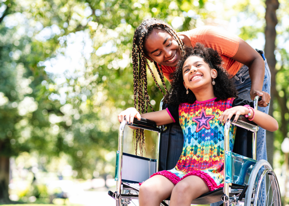 Young girl in a wheelchair at the park with her mother