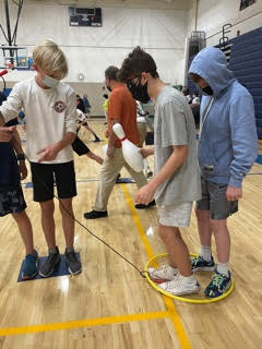 three students moving about the "lava" game in the gym