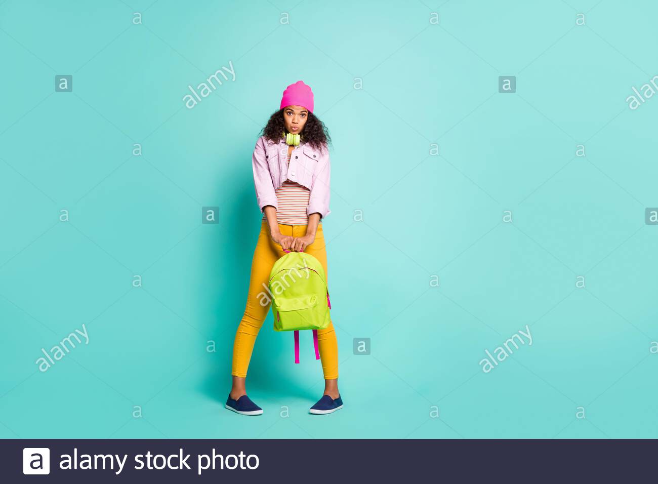 Photo of hesitating shy cute nice charming girlfriend holding school bag  with hands uncertain to know information in yellow pants pink cap headwear  Stock Photo - Alamy
